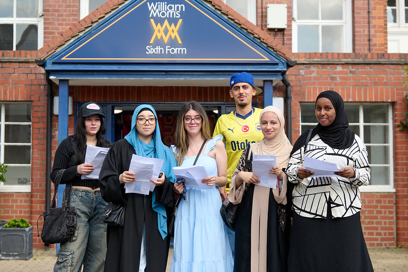 Six young people standing outside the William Morris Sixth Form College building