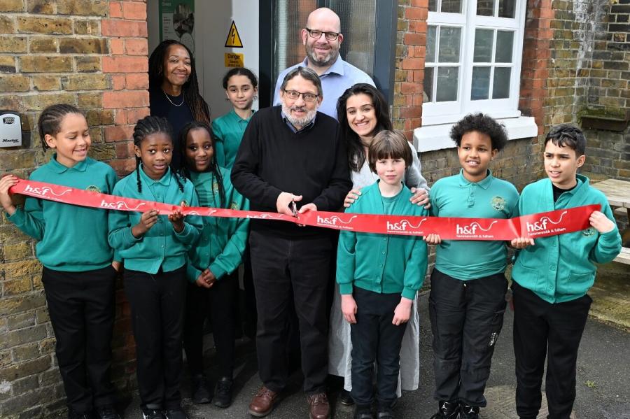 Cllr Wesley Harcourt, H&F Cabinet Member for Climate Change and Ecology (centre), cuts the ribbon alongside Kenmont Primary school pupils, executive headteacher David Collins (back) and PTA chair Nazia Chishty (right) and resident Patrice Ennis (left)