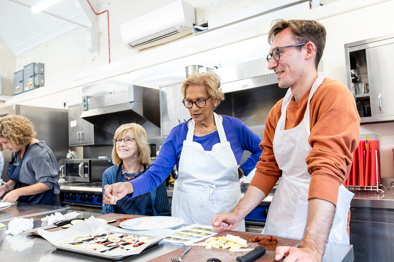 Three students learning to make aubergine parmigiana