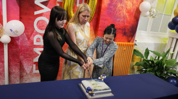 Mary Berrisford, school principal (centre) cuts celebration cake with students