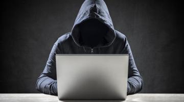 Computer hacker stealing data from a laptop