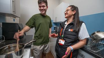 Resident Ben cooking in new kitchen with MCP trainee Lauren Wood