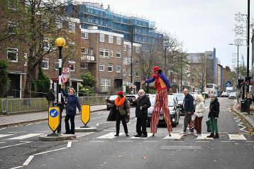 Maystar Residents’ Association committee members, including Debbie Golt (left) and Michael Gannon, MRA Co-Chair (middle) walking across the zebra crossing on North End Road with stilt-walker Ella the Great