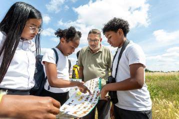 Cllr Wesley Harcourt discovering the fauna and flora of Wormwood Scrubs meadow with students of Old Oak primary school