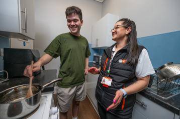 Resident Ben cooking in new kitchen with MCP trainee Lauren Wood