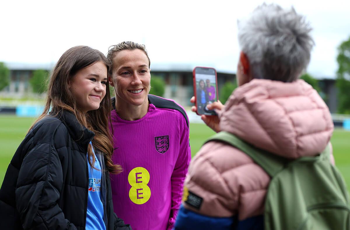 Lucy Bronze poses for a photo with a fan at the end of England's training session