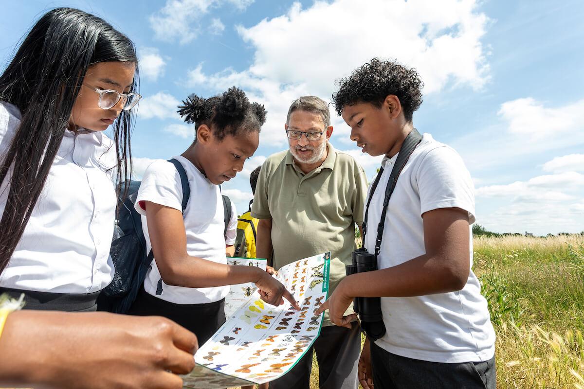 Cllr Wesley Harcourt discovering the fauna and flora of Wormwood Scrubs meadow with students of Old Oak primary school