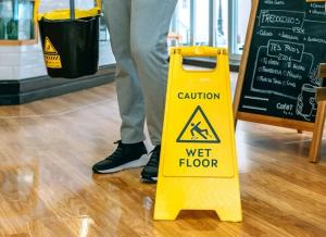 A yellow cautionary sign on a wooden floor warning that the floor is wet.