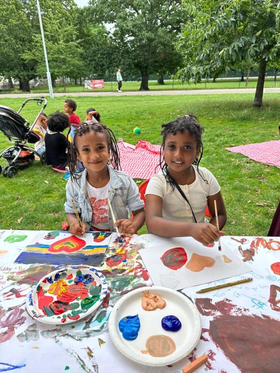 Two girls paint pictures at Art in the Park