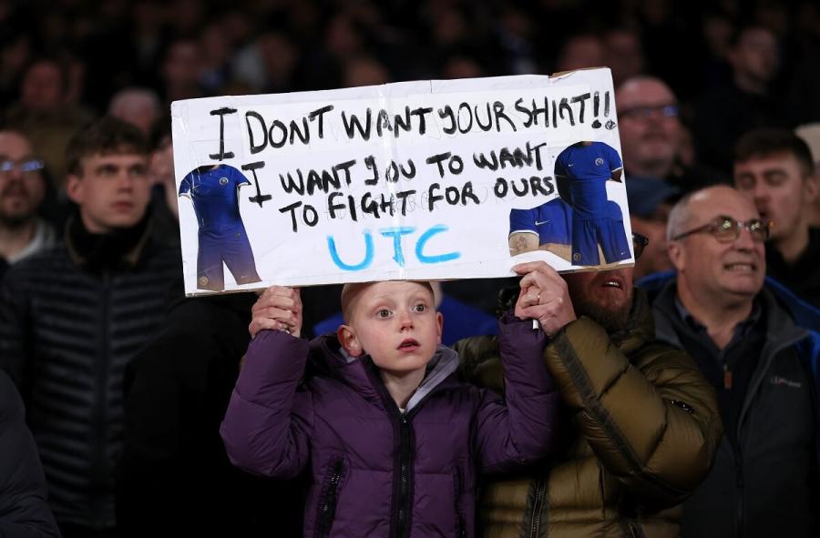 A young Chelsea fan holds up a banner reading 'I don't want your shirt! I want you to want to fight for ours' during game with Arsenal.