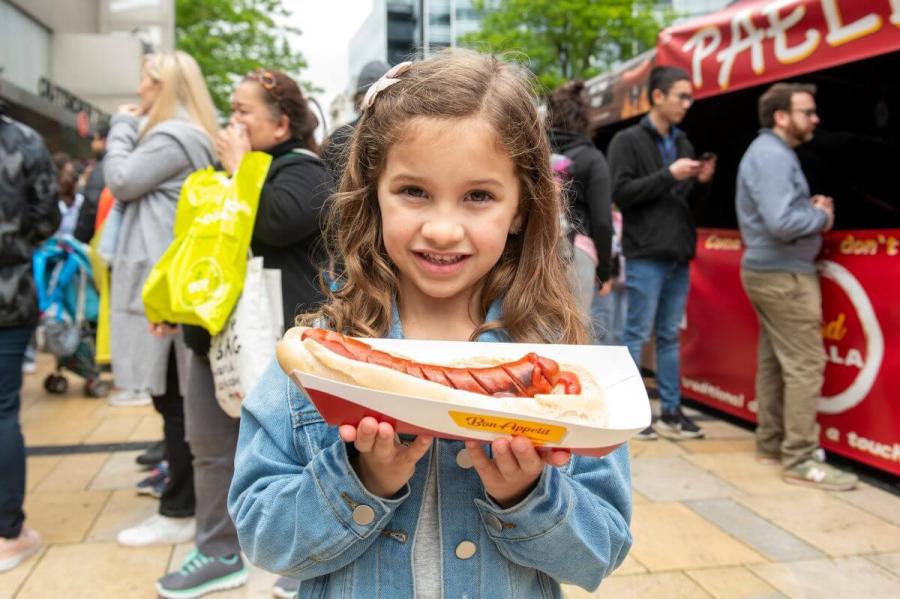 Little girl with hotdog at H&F's Hammersmith Summer Street Fest 2024