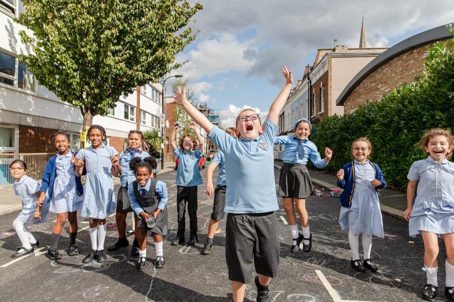 Young school childreb in blue and grey uniform enjoying playing in a car free street.
