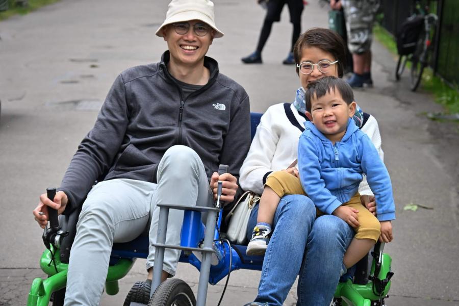A young family of three trialling a two-seat cycle at H&F's Festival of Cycling in Ravenscourt Park, Hammersmith
