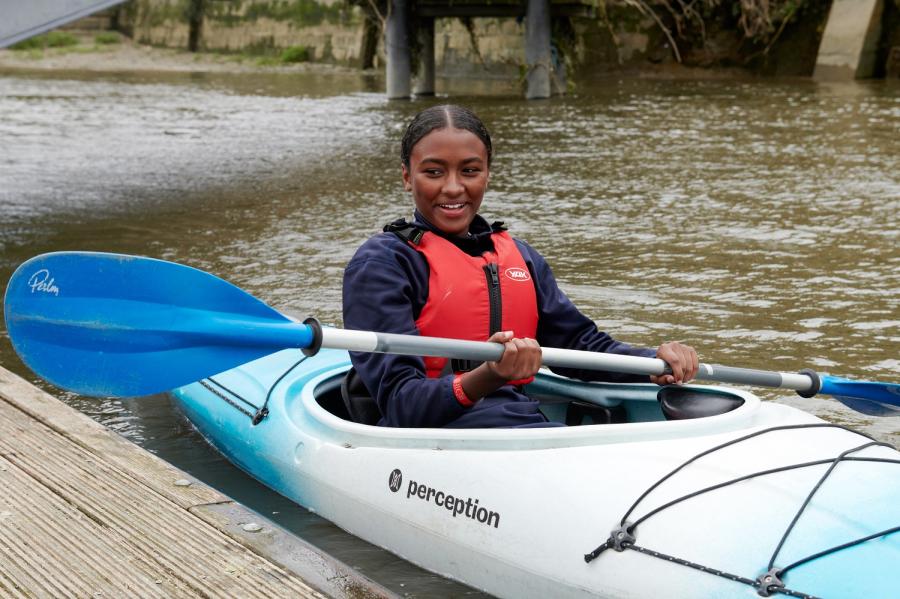 A girl pushes off the dock in her blue kayak