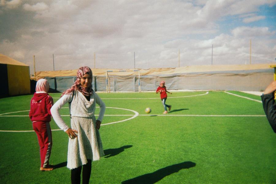Young refugees playing football on a artificial playing surface