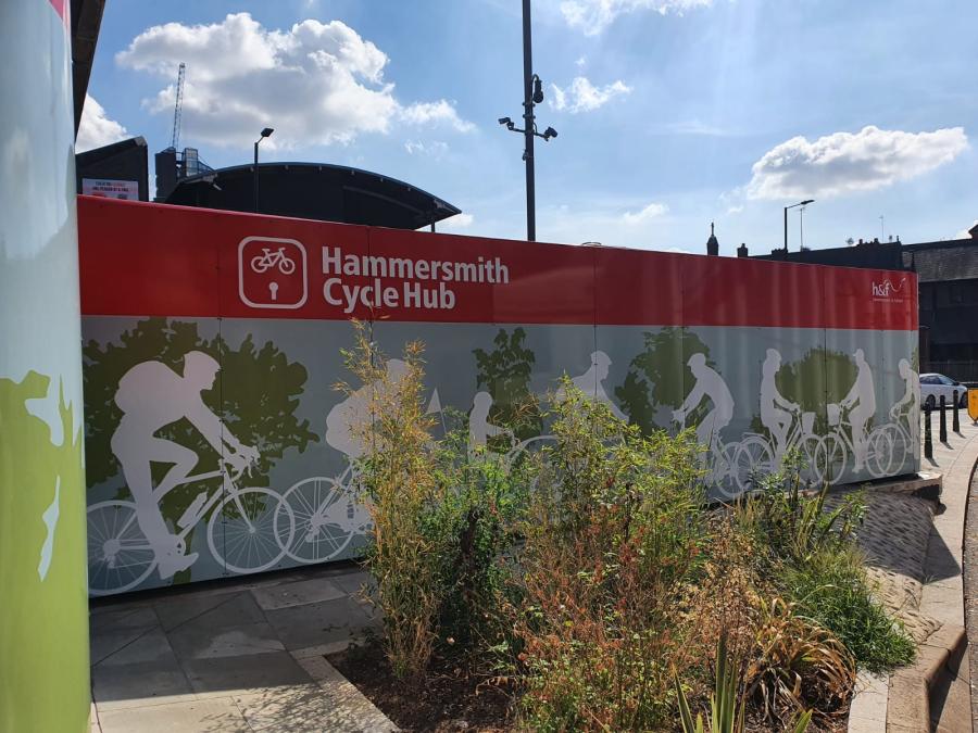 Cycle storage with red and blue vinyl graphics and white shapes of cyclists attached to the outside of the hub.