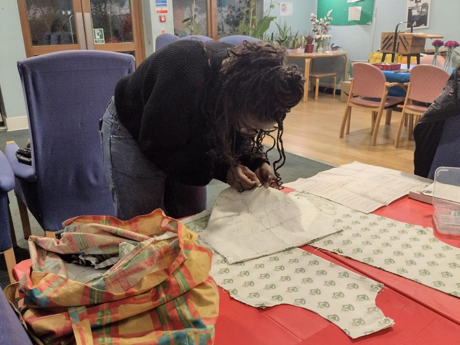 A woman in the early stages of hand-sewing a blouse