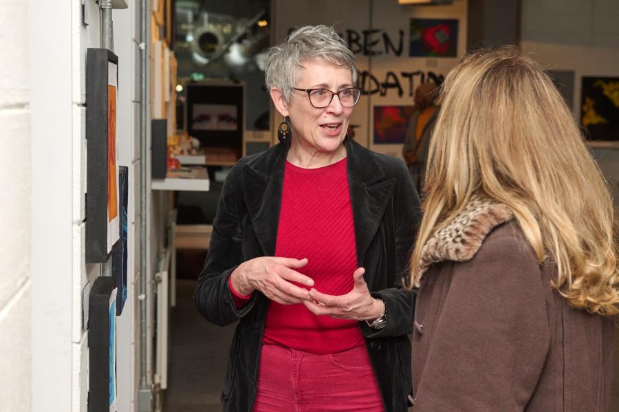 Two women talking in front of a wall of art