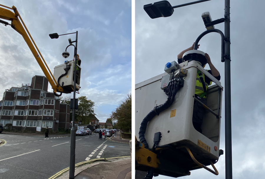 Construction worker on a crane working on a CCTV camera attached to a streetlight
